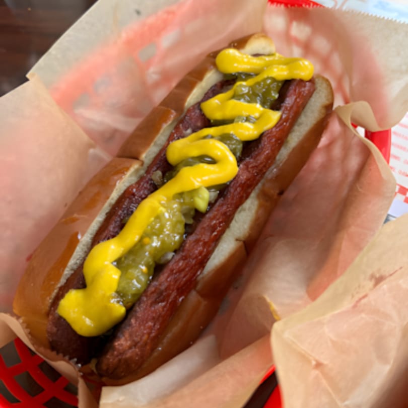 A Jordan's Hot Dog with mustard and relish in a red basket lined with paper.